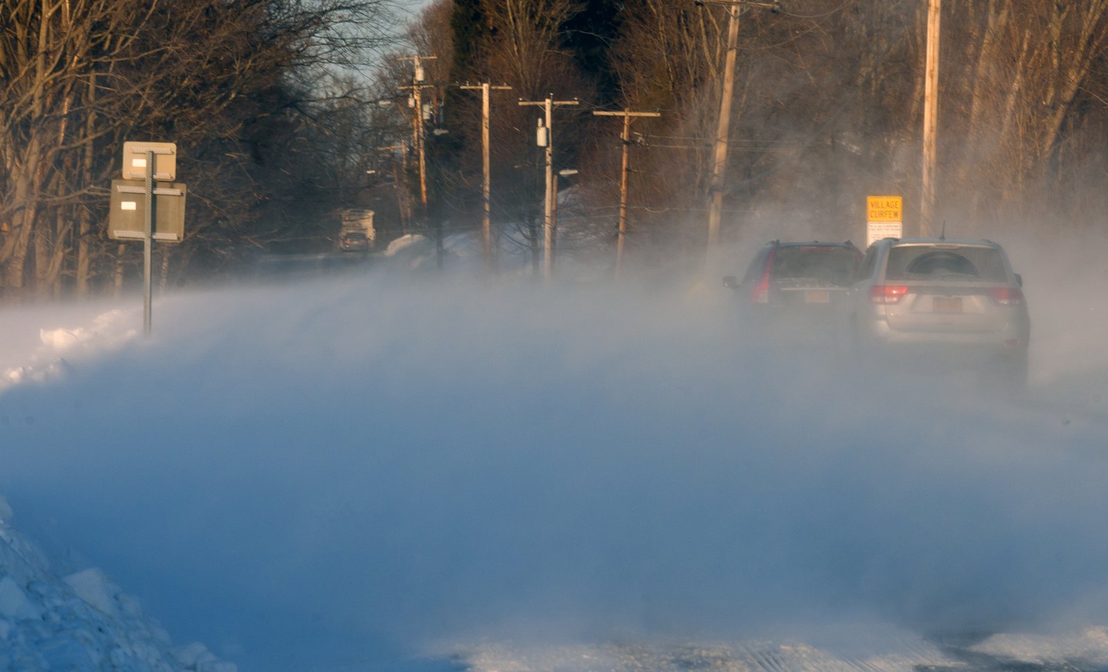 Cars driving through blowing snow on a winter road